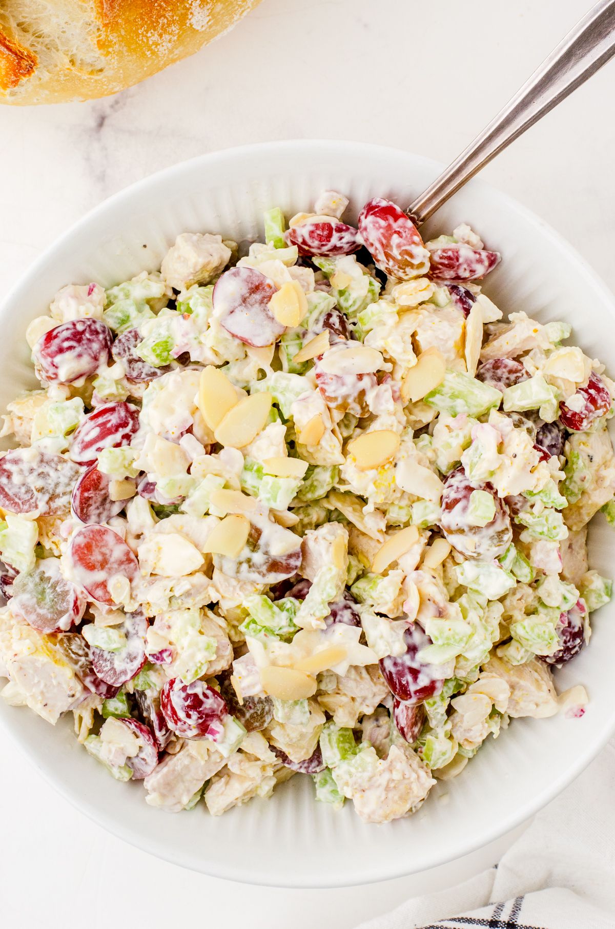 A bowl of chicken salad with sliced almonds on the top.