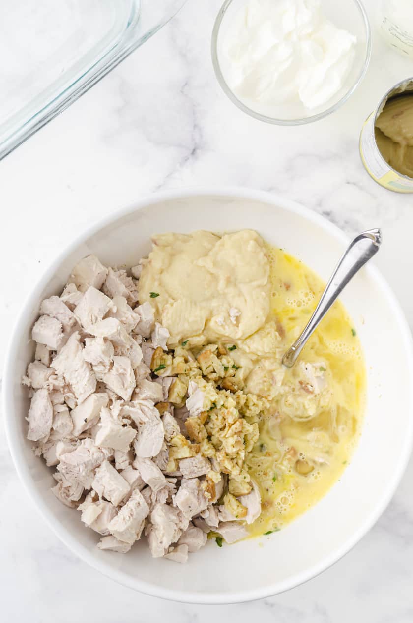 Mixing together ingredients for chicken and stuffing casserole recipe in a mixing bowl.