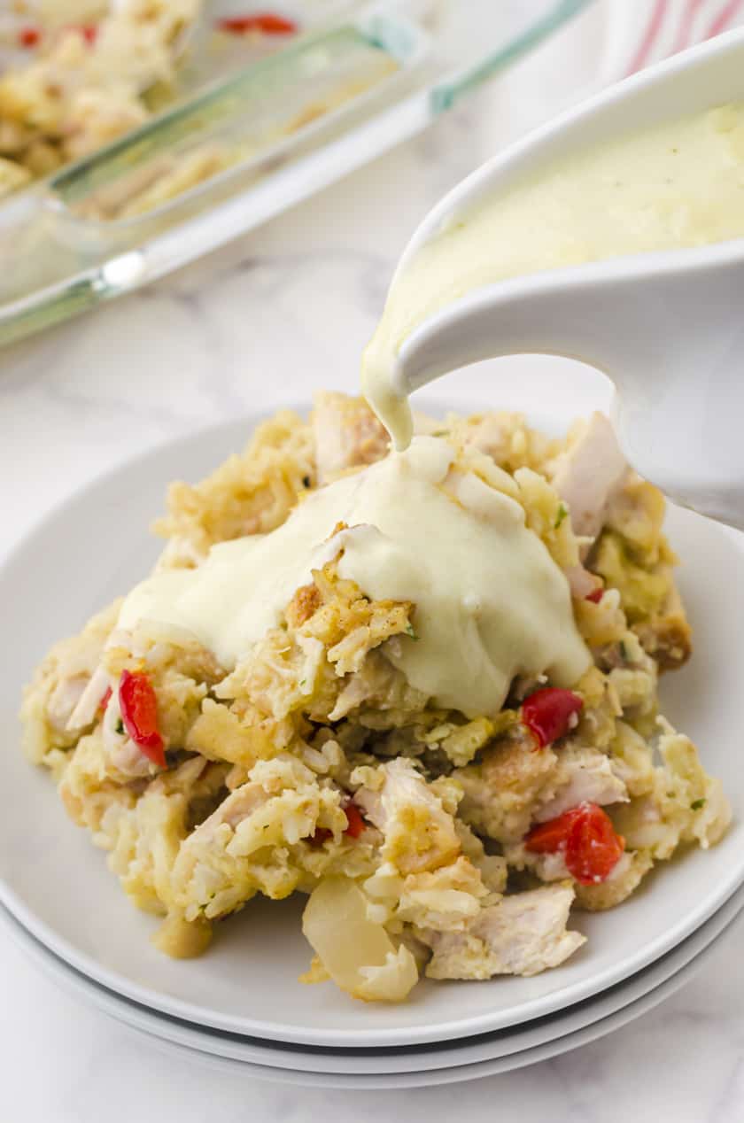 Serving of chicken rice casserole with creamy sauce being poured over it.