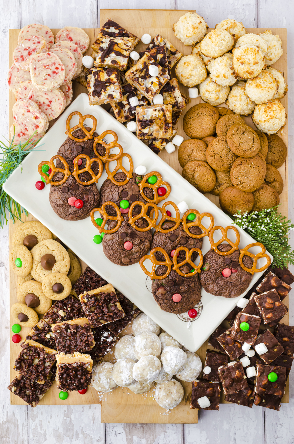 A large charcuterie board filled with dozens of different kinds of Christmas cookies, with the center plate filled with Reindeer Brownie Cookies.