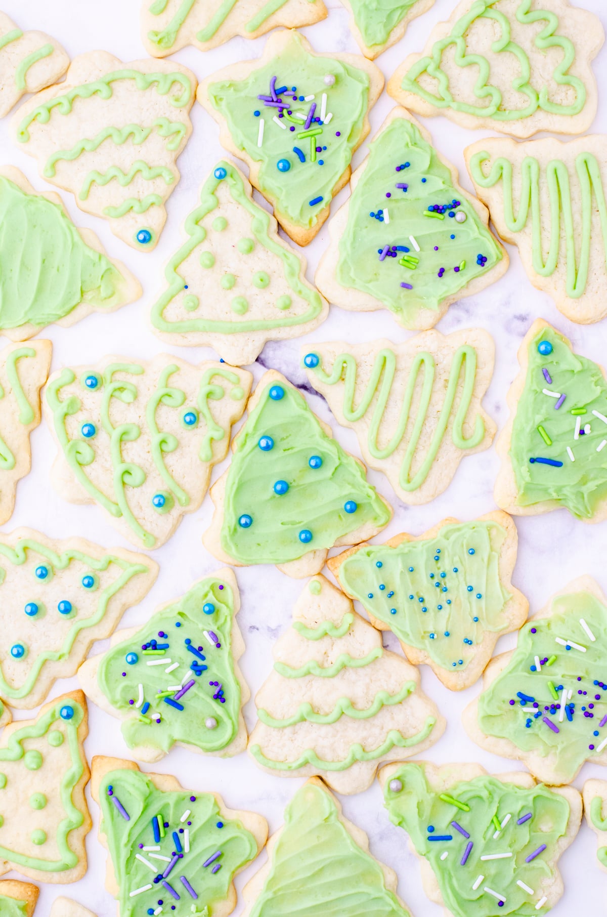 Christmas sugar cookies in the shape of trees with green icing and sprinkles
