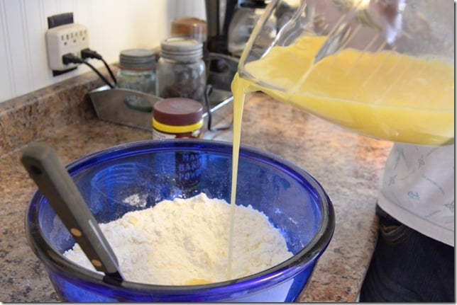 pouring liquid ingredients into dry ingredients for rolled sugar cookies