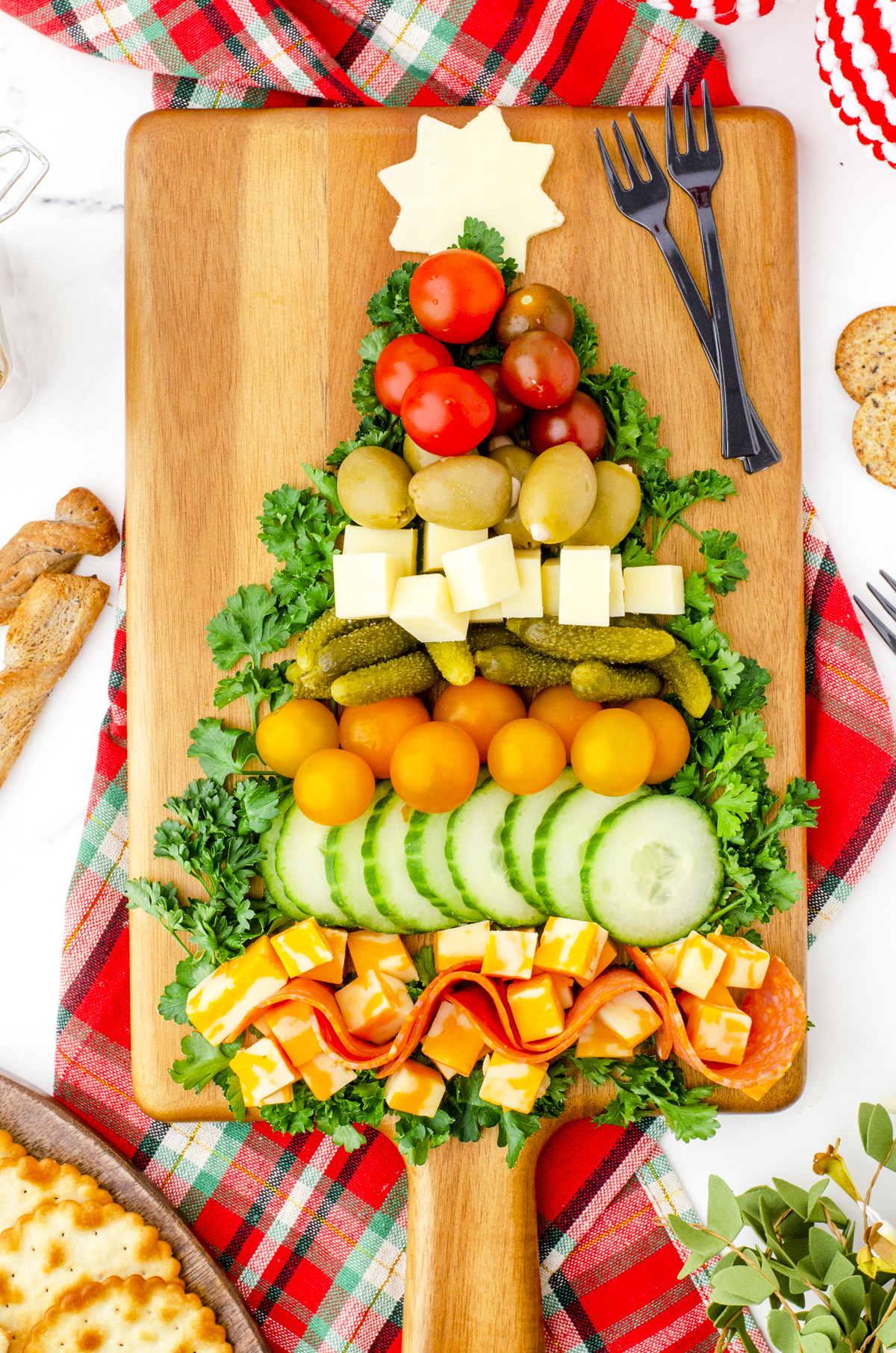 a charcuterie board with a variety of meat, cheeses, and veggies in the shape of a Christmas tree