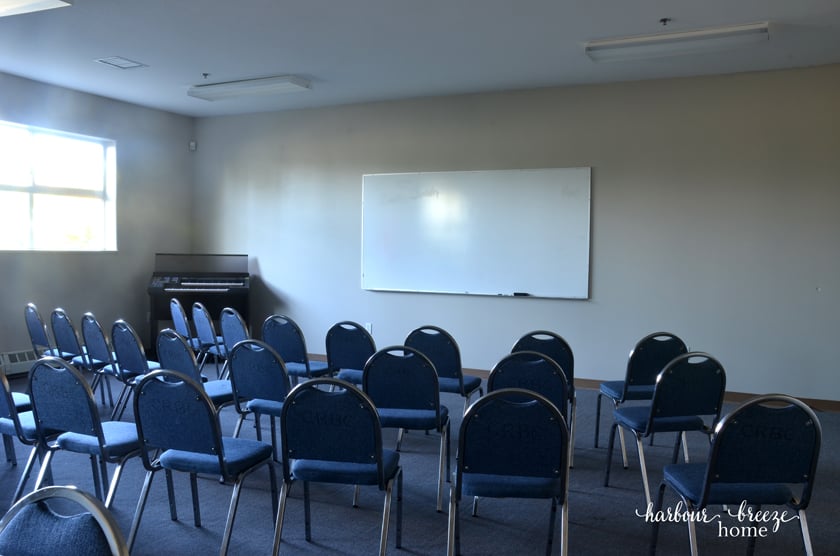 Chairs facing a wall with a white board on it.