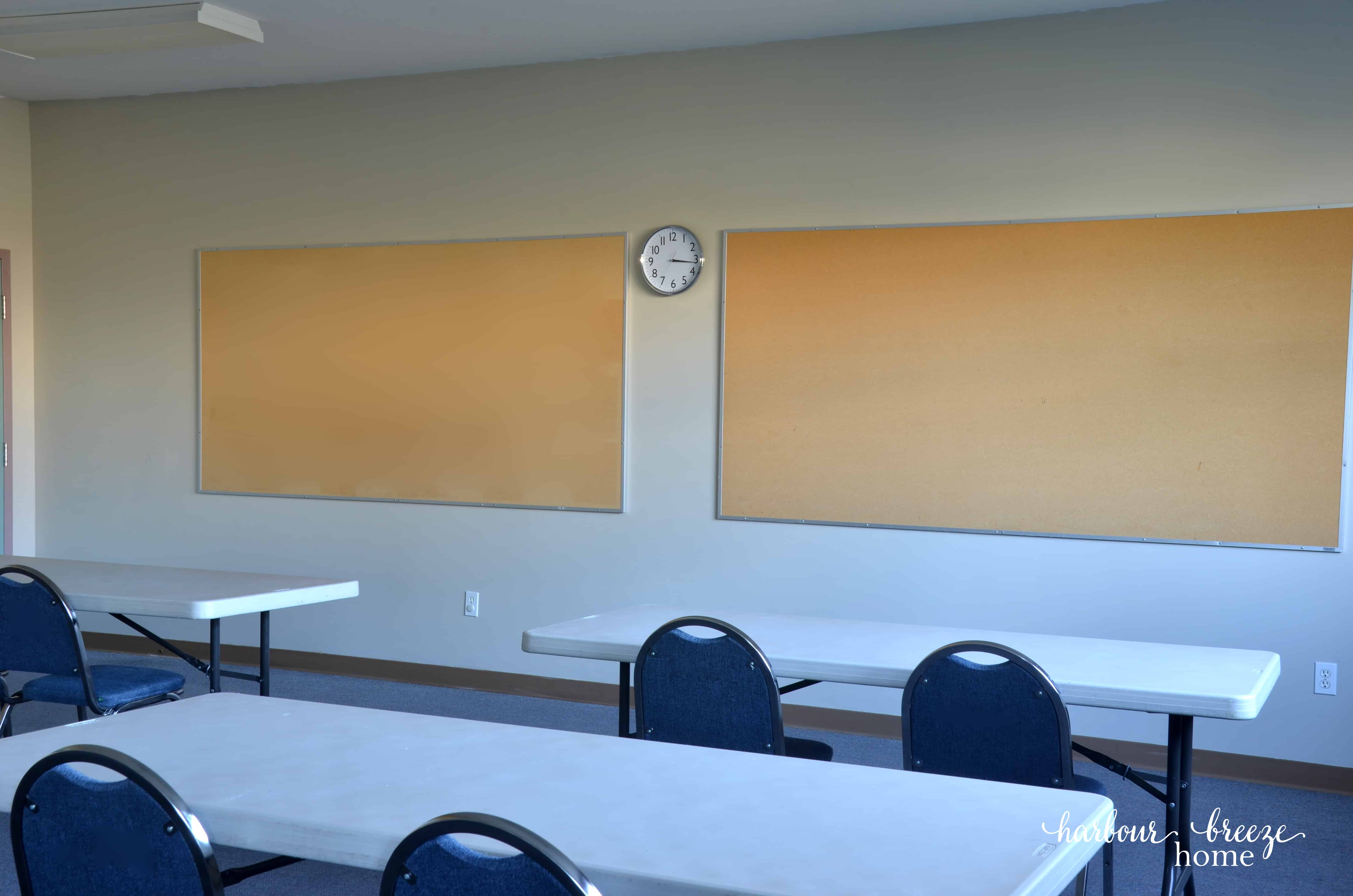Two bulletin boards on a wall with a clock in the middle
