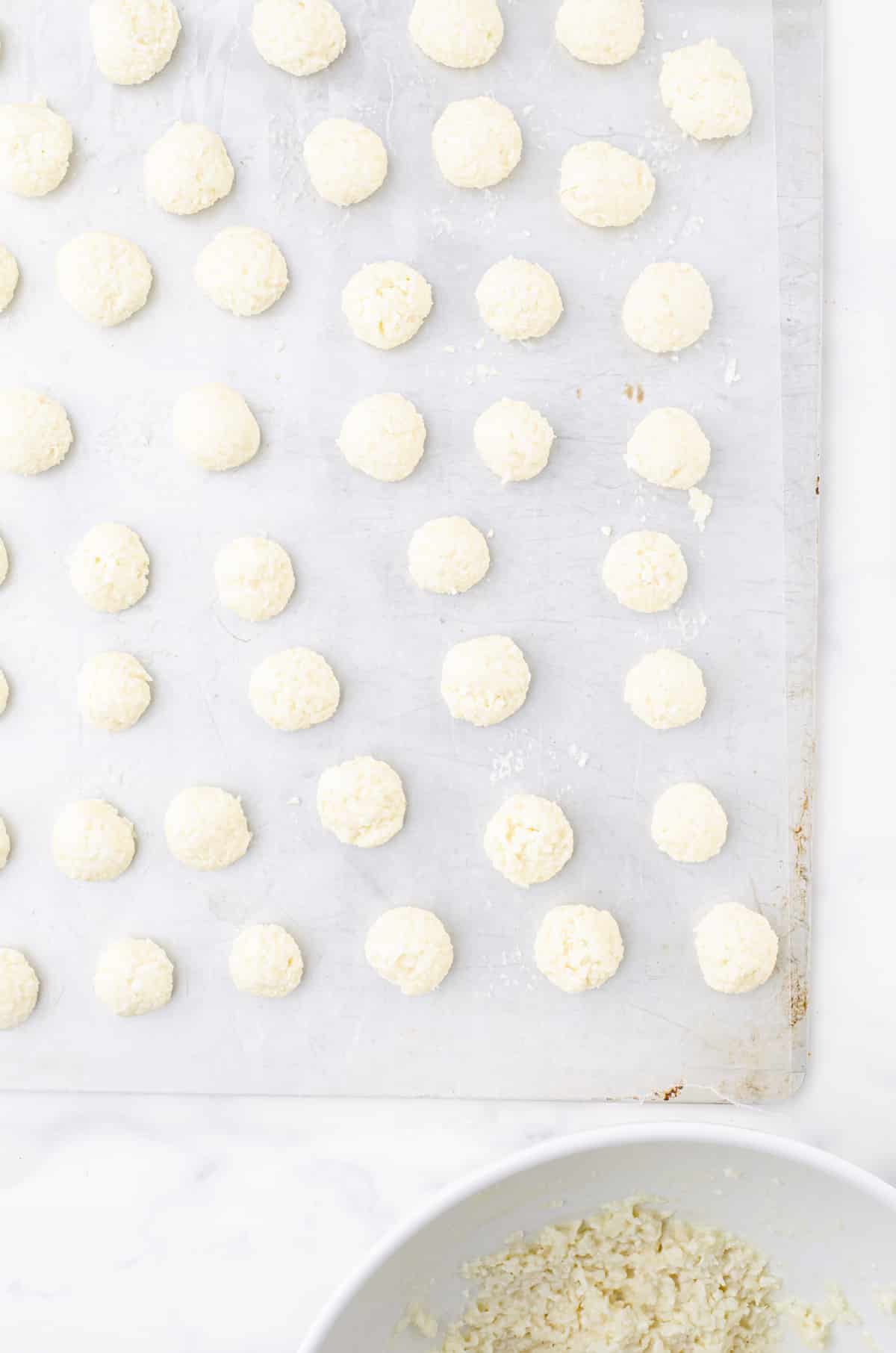 No bake coconut balls on a parchment paper lined cookie sheet
