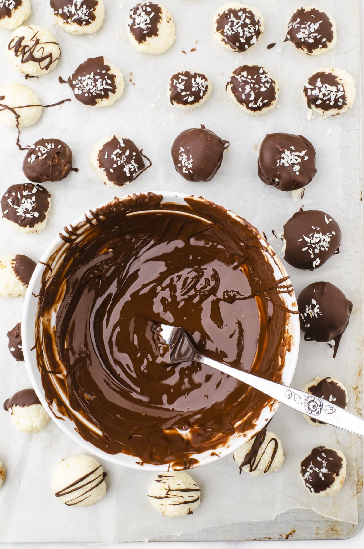 Coconut balls no bake recipe being dipped in a bowl of melted chocolate