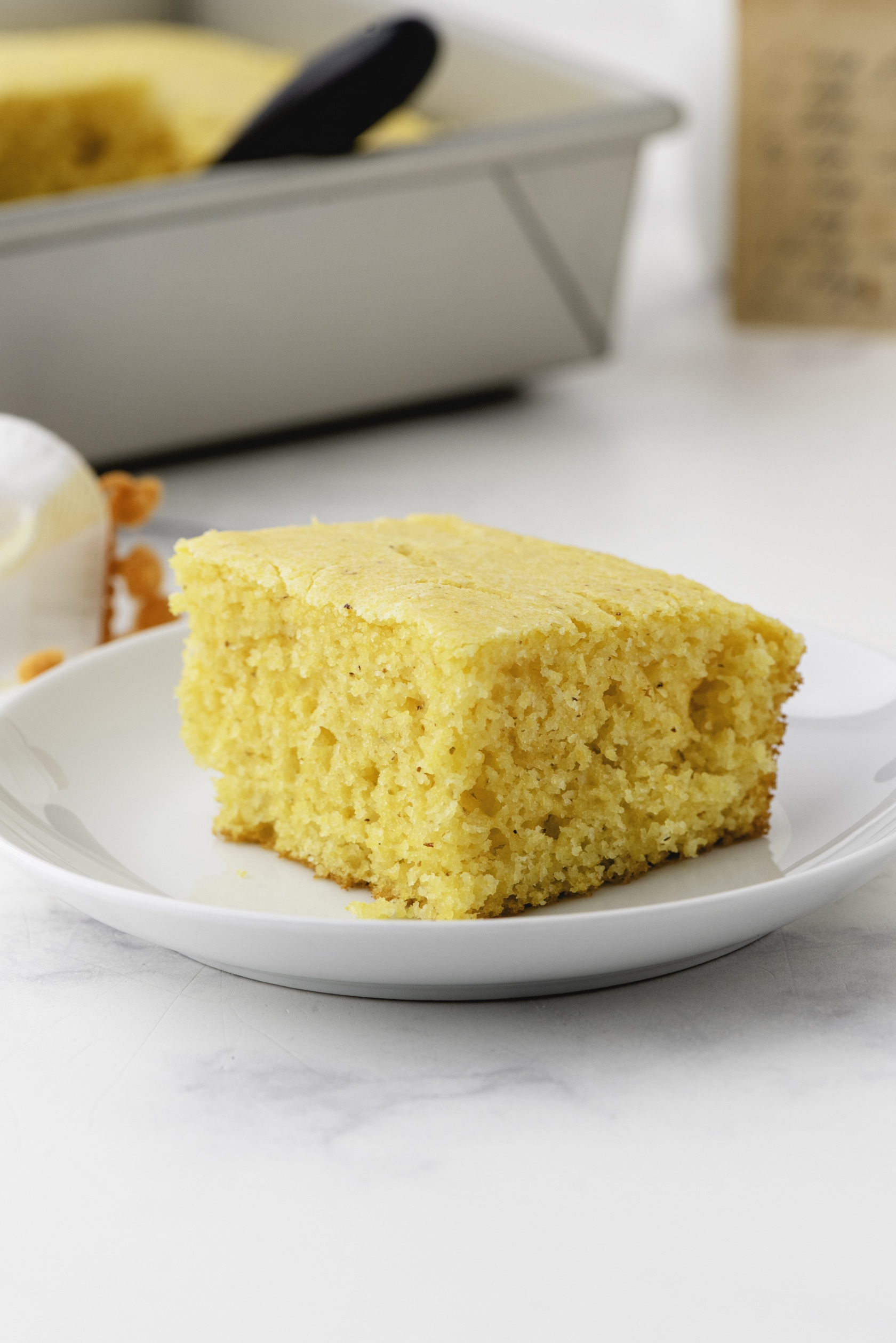 A slice of simple cornbread on a serving plate.