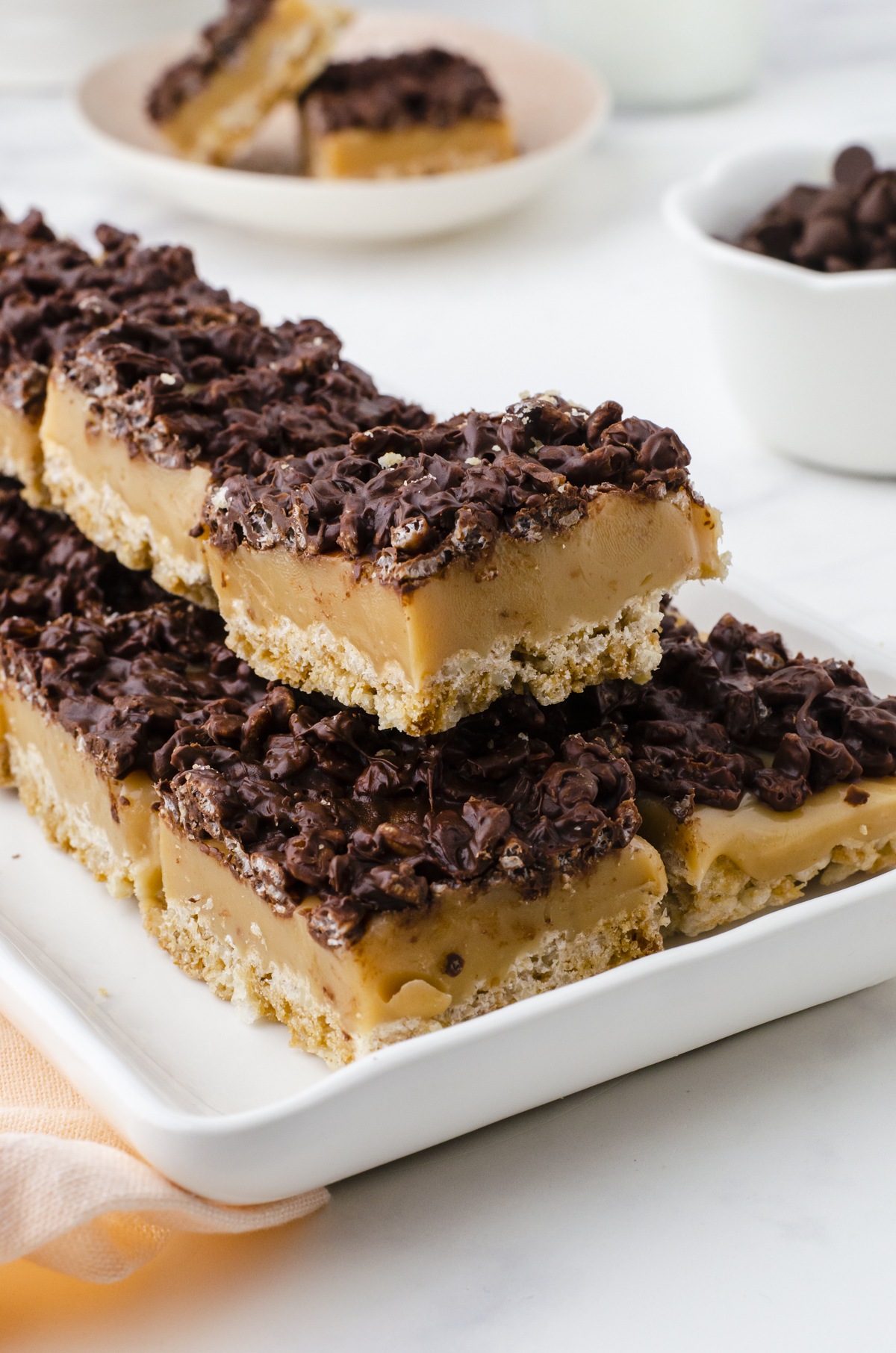 Chocolate Caramel Rice Krispy Bars cut and stacked on a cookie platter.