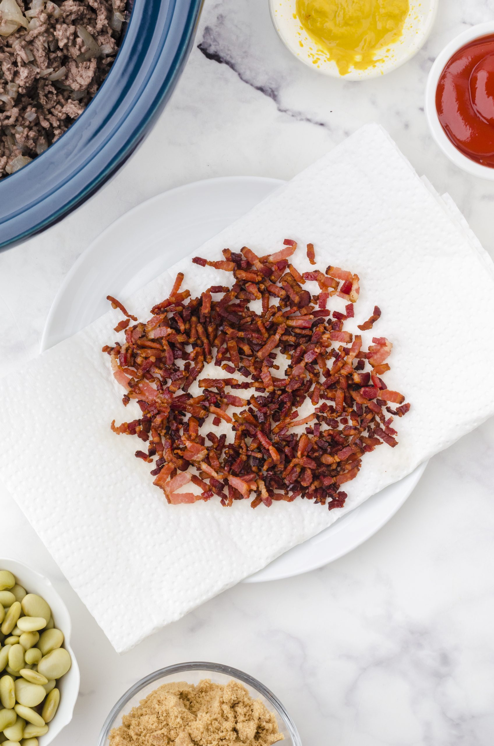 Crispy bacon bits sitting on a paper towel in preparation to be added to the crock pot for crock pot baked beans.