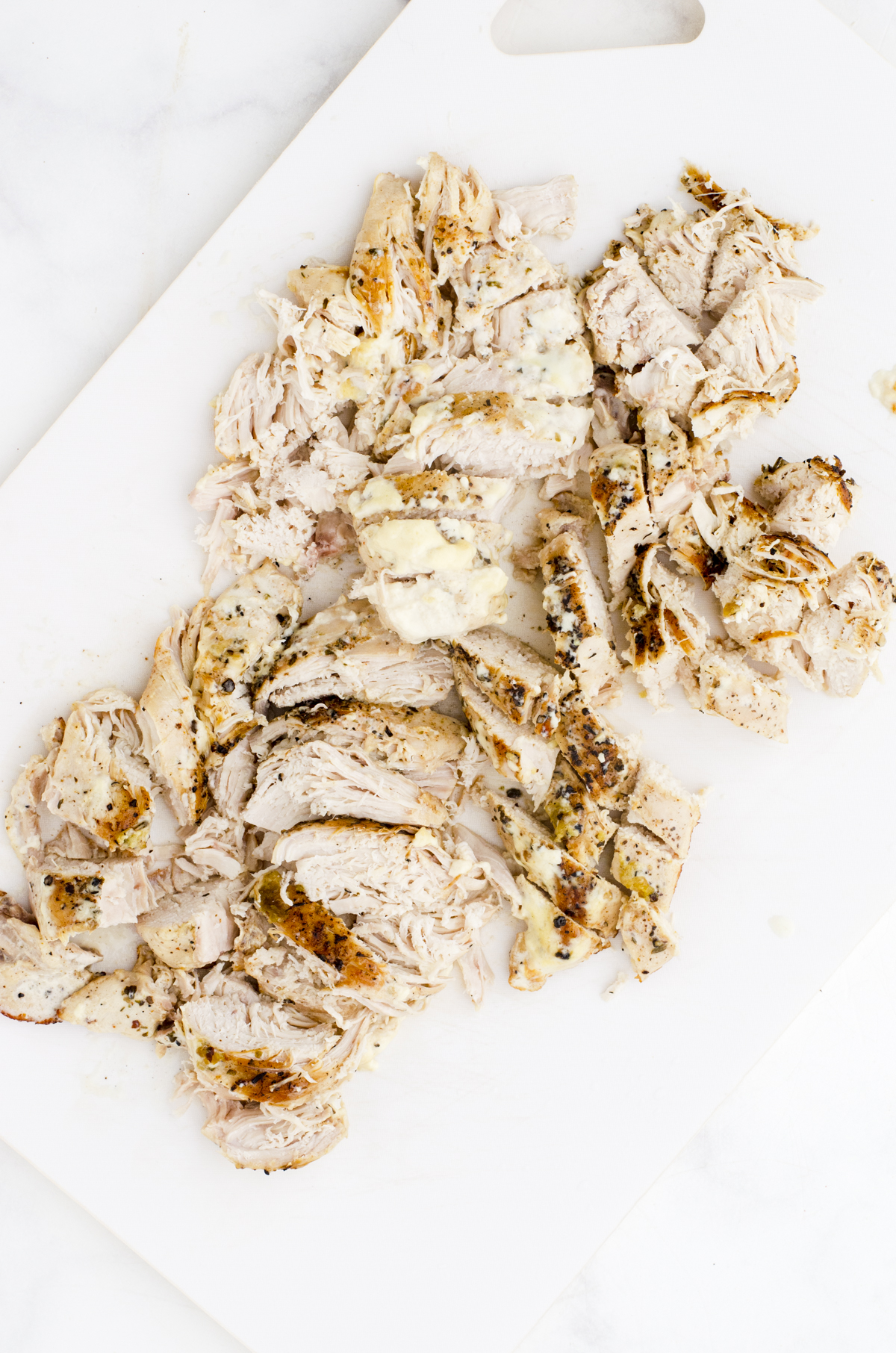 Chicken breasts cut up on a cutting board.