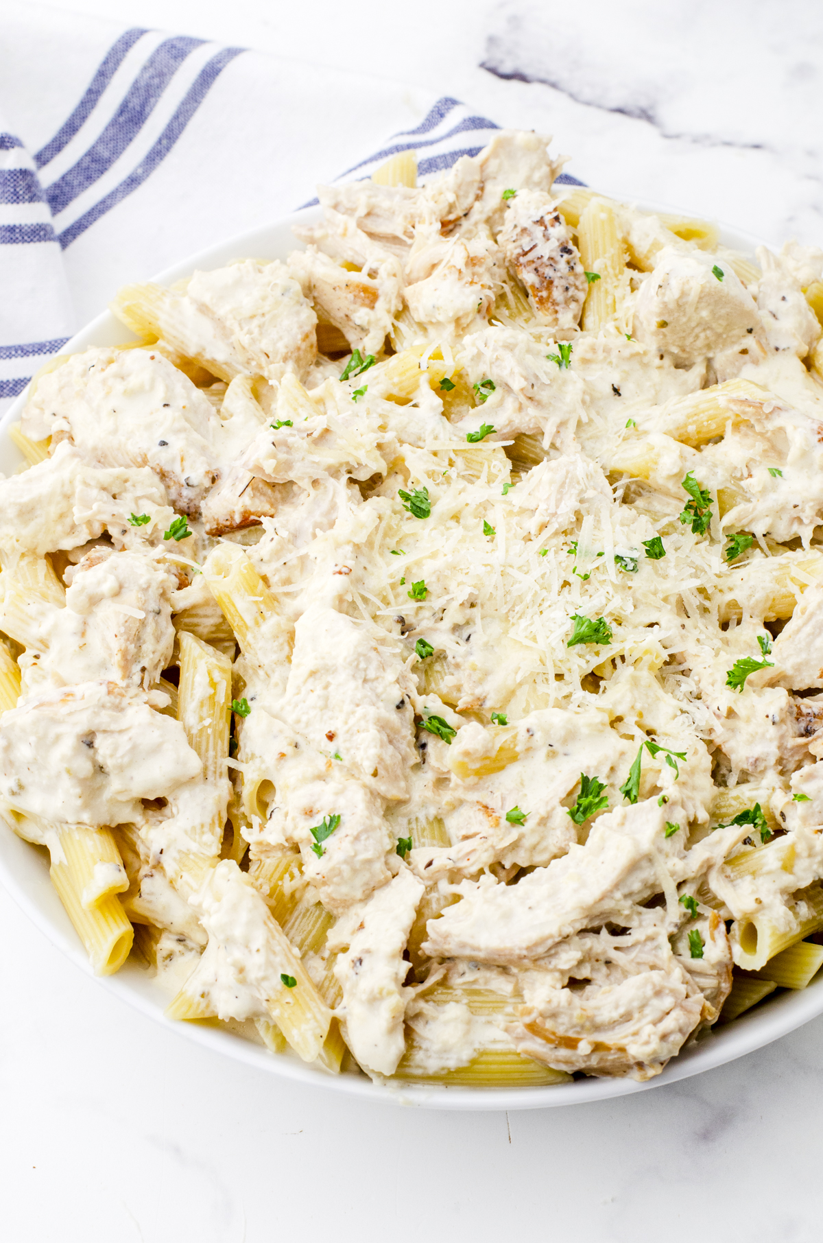 Crock pot chicken alfredo in a serving bowl poured over pasta.