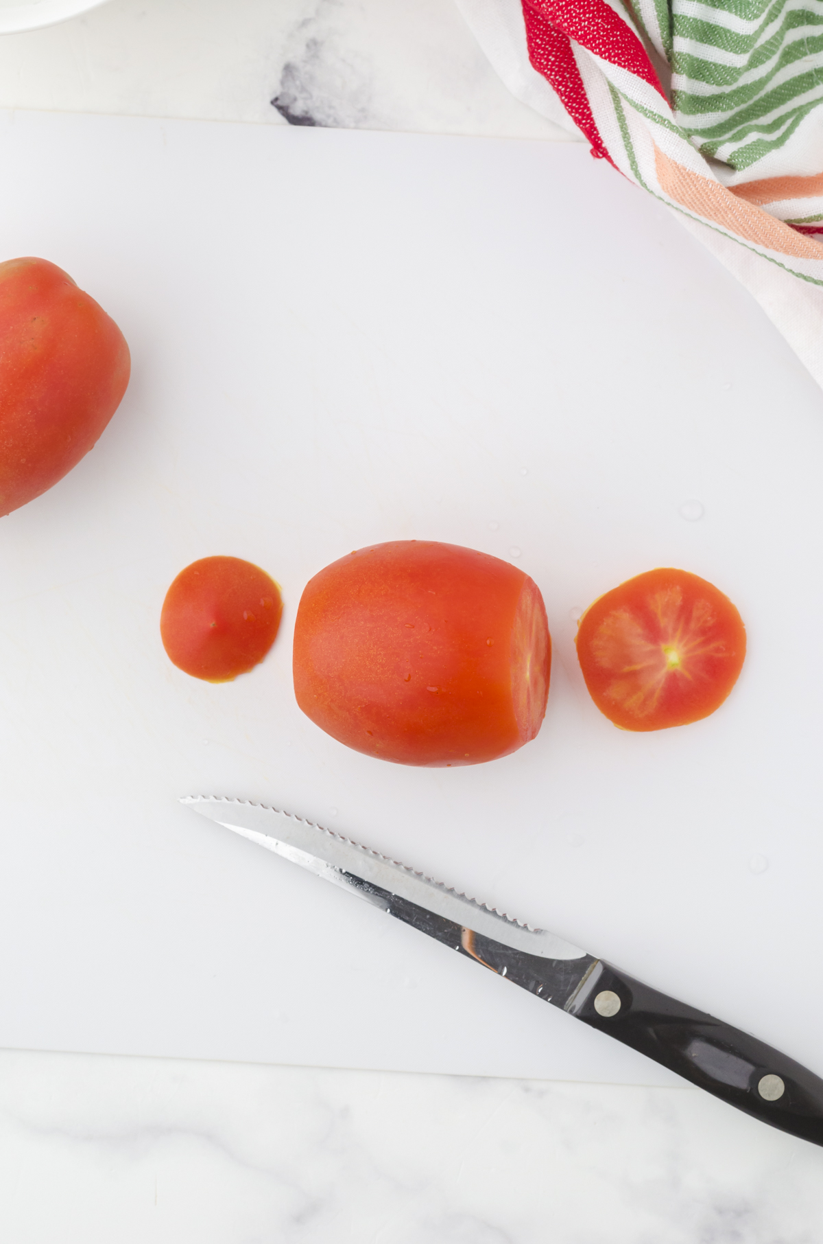 The top and bottom of a tomato cut off in preparation for deseeding a tomato