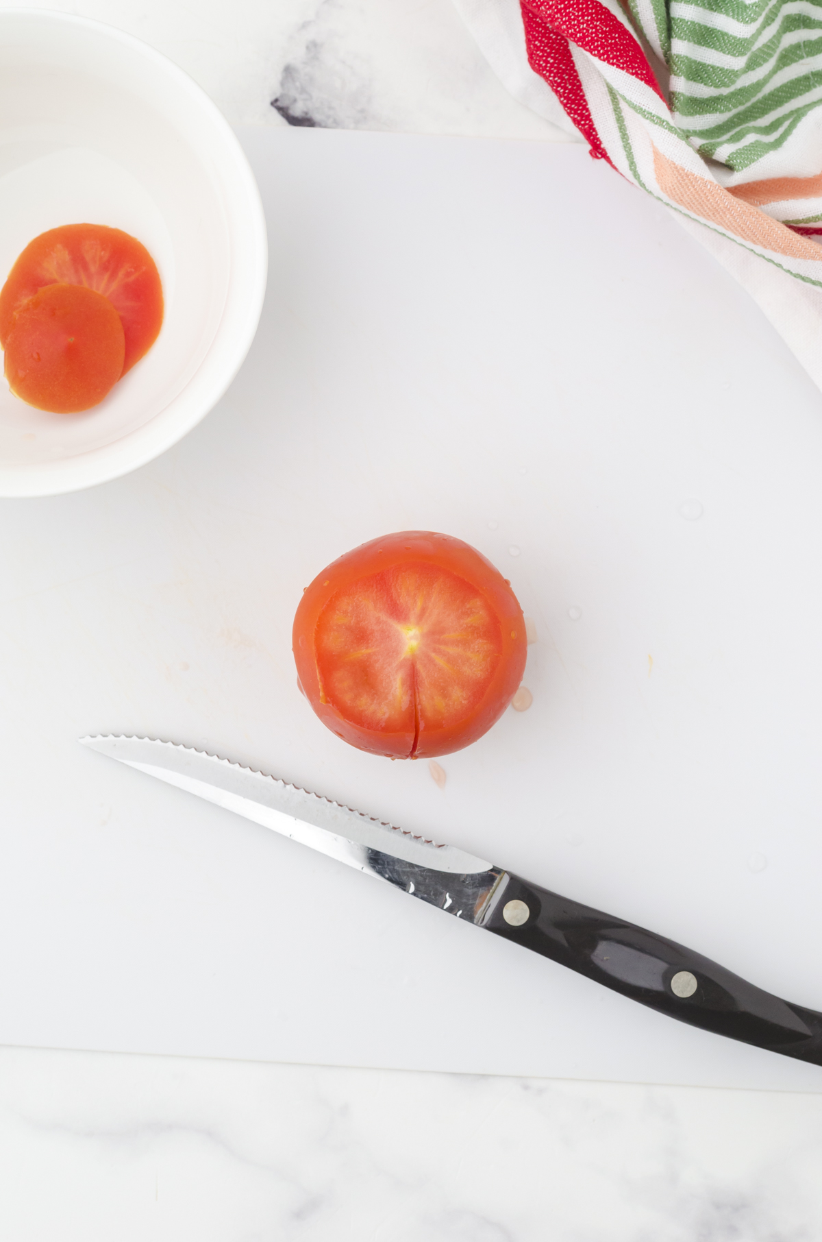 A small slice on the side of a tomato in preparation for deseeding it.
