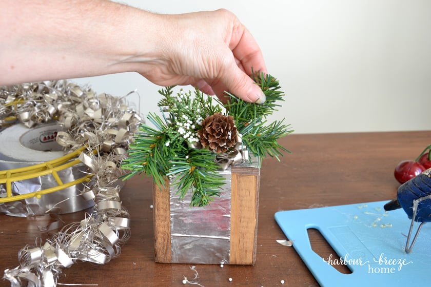 adding faux greenery to a wooden block gift