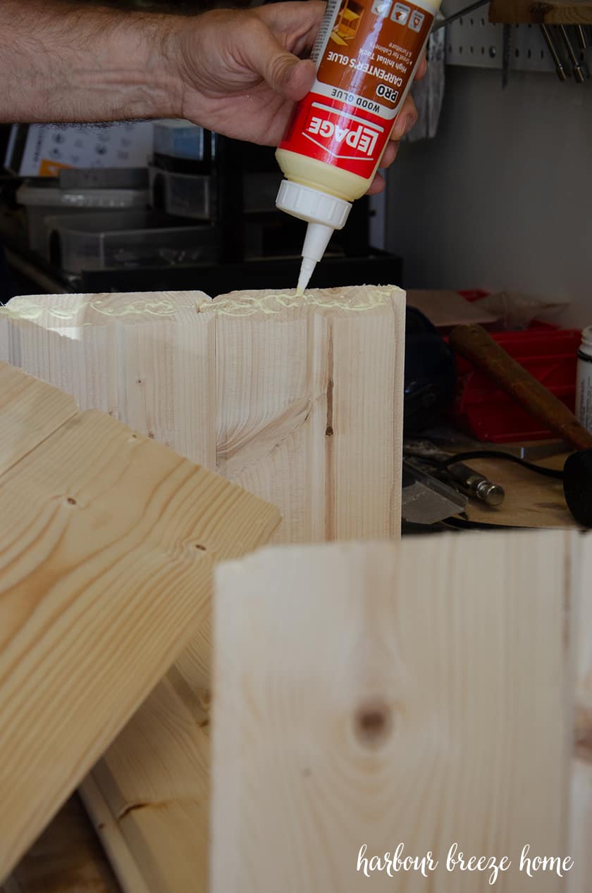 Glue being squeezed on to the corners of the wood where the top of bedside table will be attached.