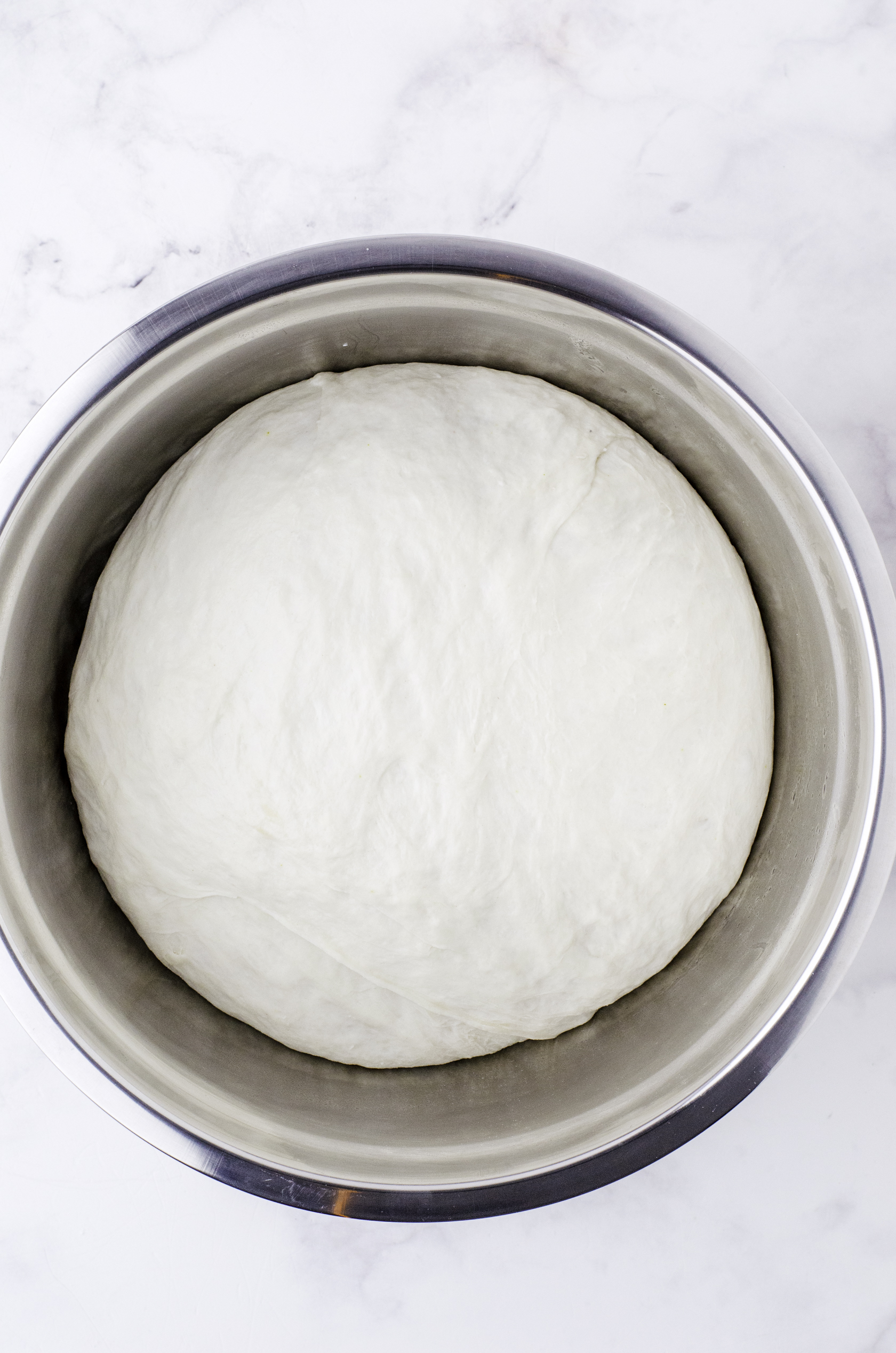 Sourdough bread dough after it has risen to over double in size in a large metal bowl.