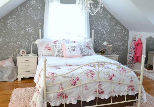 Bed with white bedspread and pink roses with a gray wall with white hand painted flowers behind