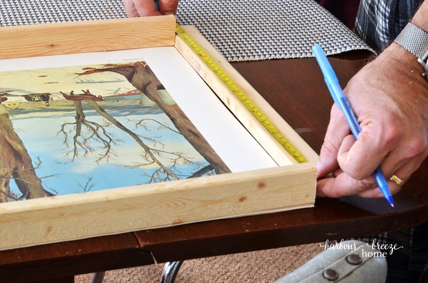 Using a measuring tape to measure the length to cut the sides of a DIY poster or picture frame