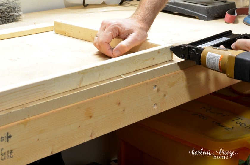 Using a brad nailer to attach the 4 corners of a homemade picture frame together.