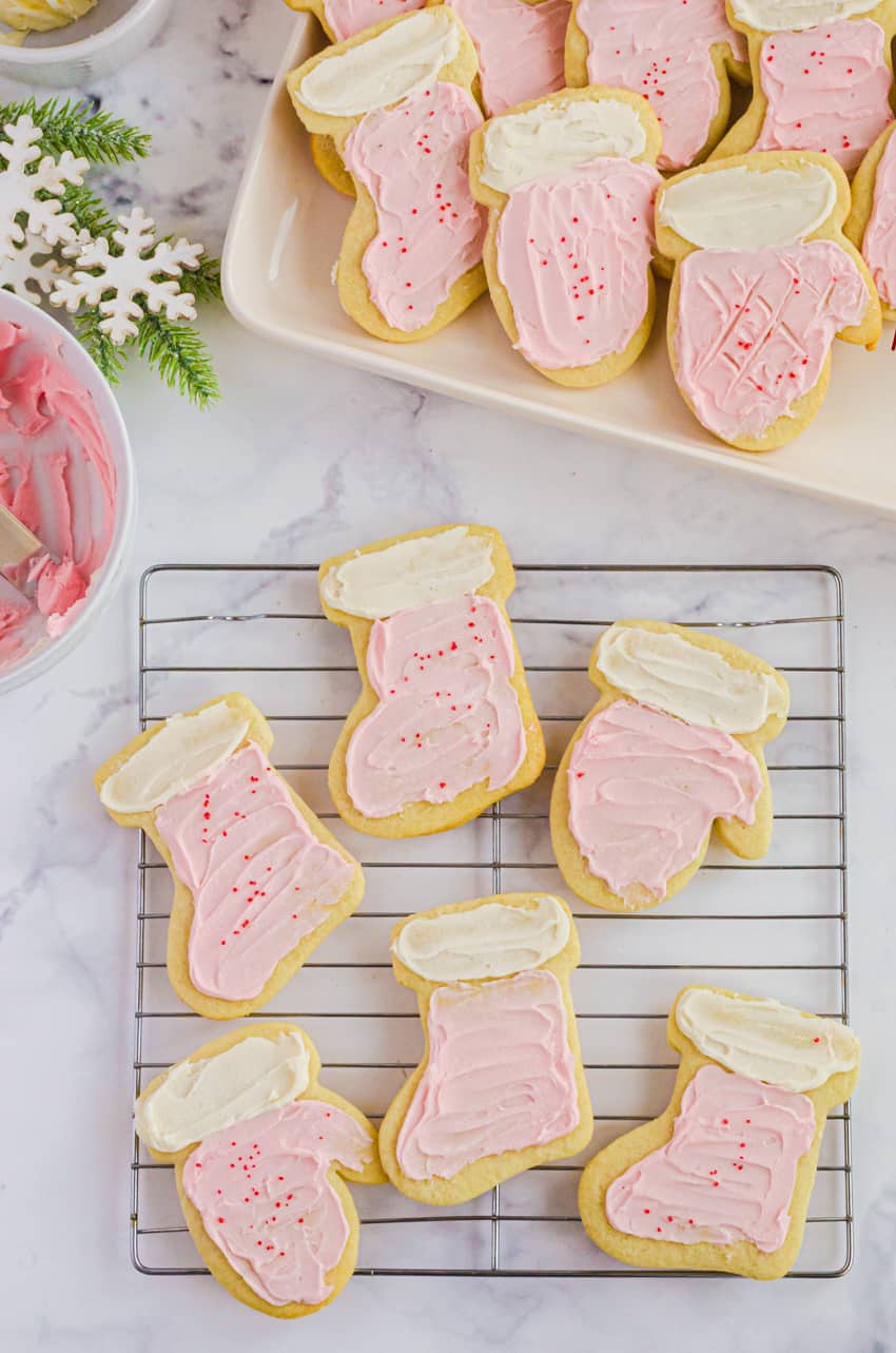 Frosted rolled sugar cookies on a tray with a bowl of easy frosting beside it.
