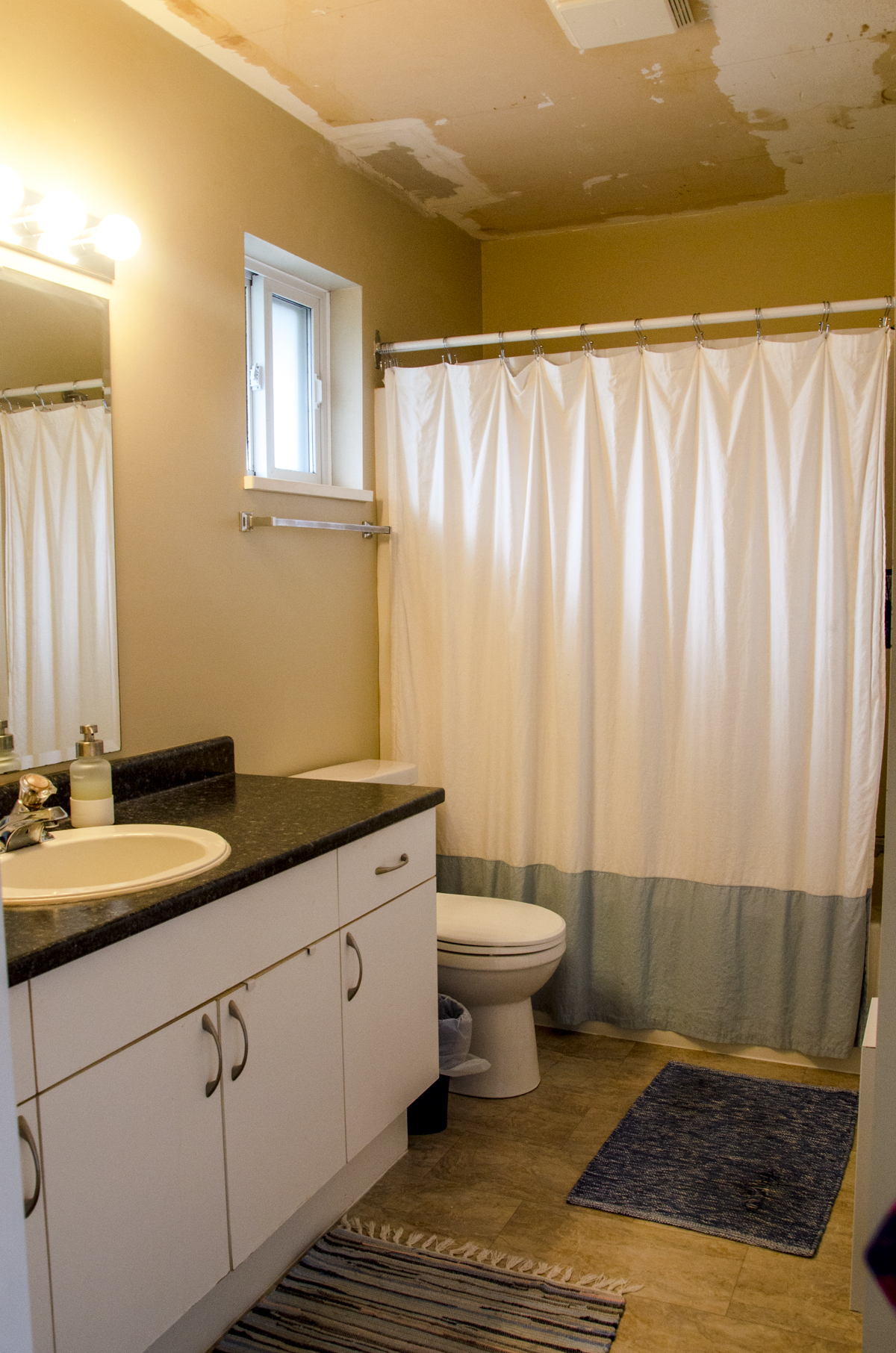 A basic builder grade bathroom with tan walls before the evergreen fog paint color makeover.