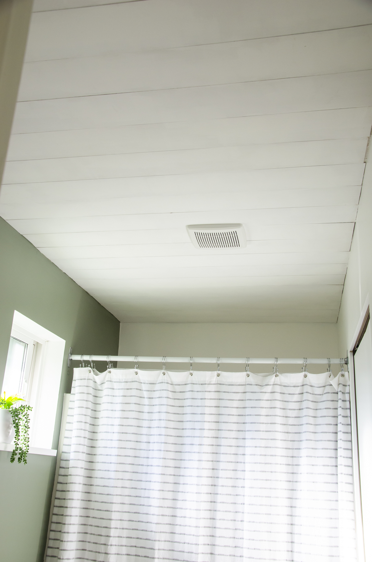 A faux shiplap wall in a small bathroom.