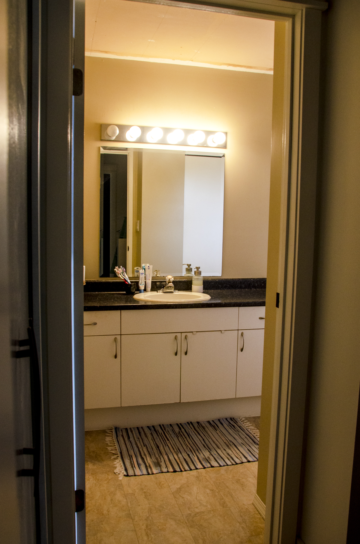 The vanity and light area with a dated look before we did an evergreen fog paint makeover with new lights and new mirror.