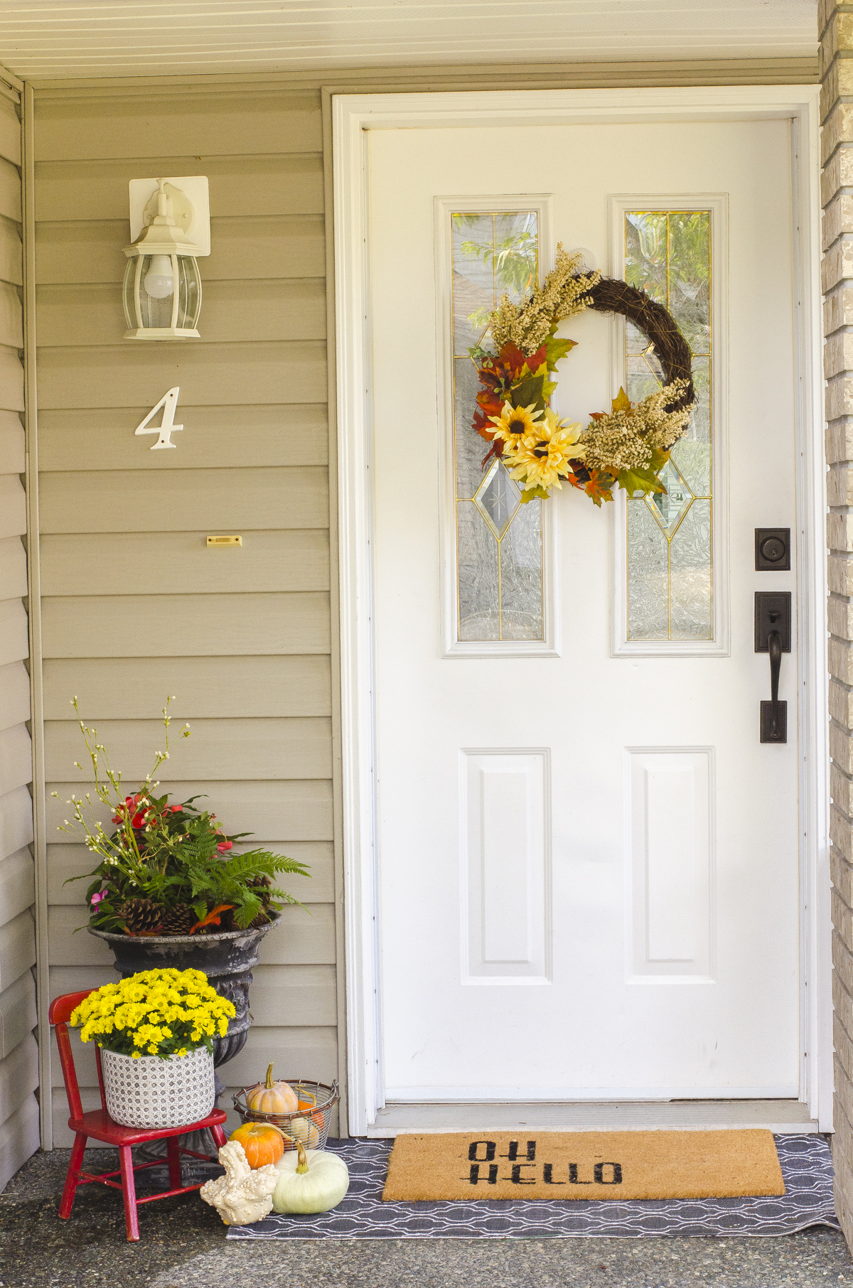 Fall mums in a pot beside a front door.