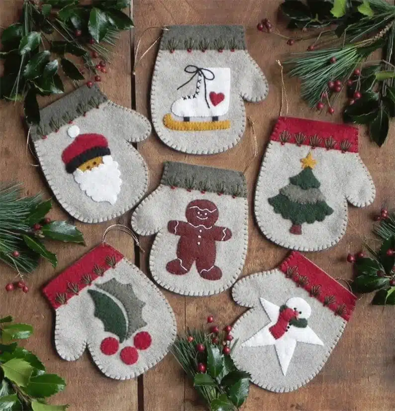 Felt Christmas ornaments in the shape of mittens with different Christmas designs on the front.