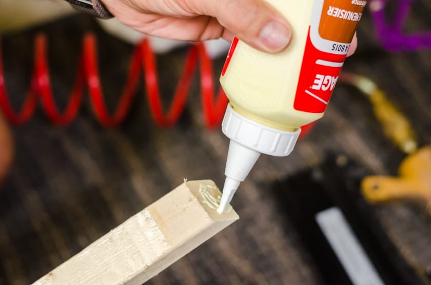Wood glue being squeezed onto the corners of a floating frame for canvas.