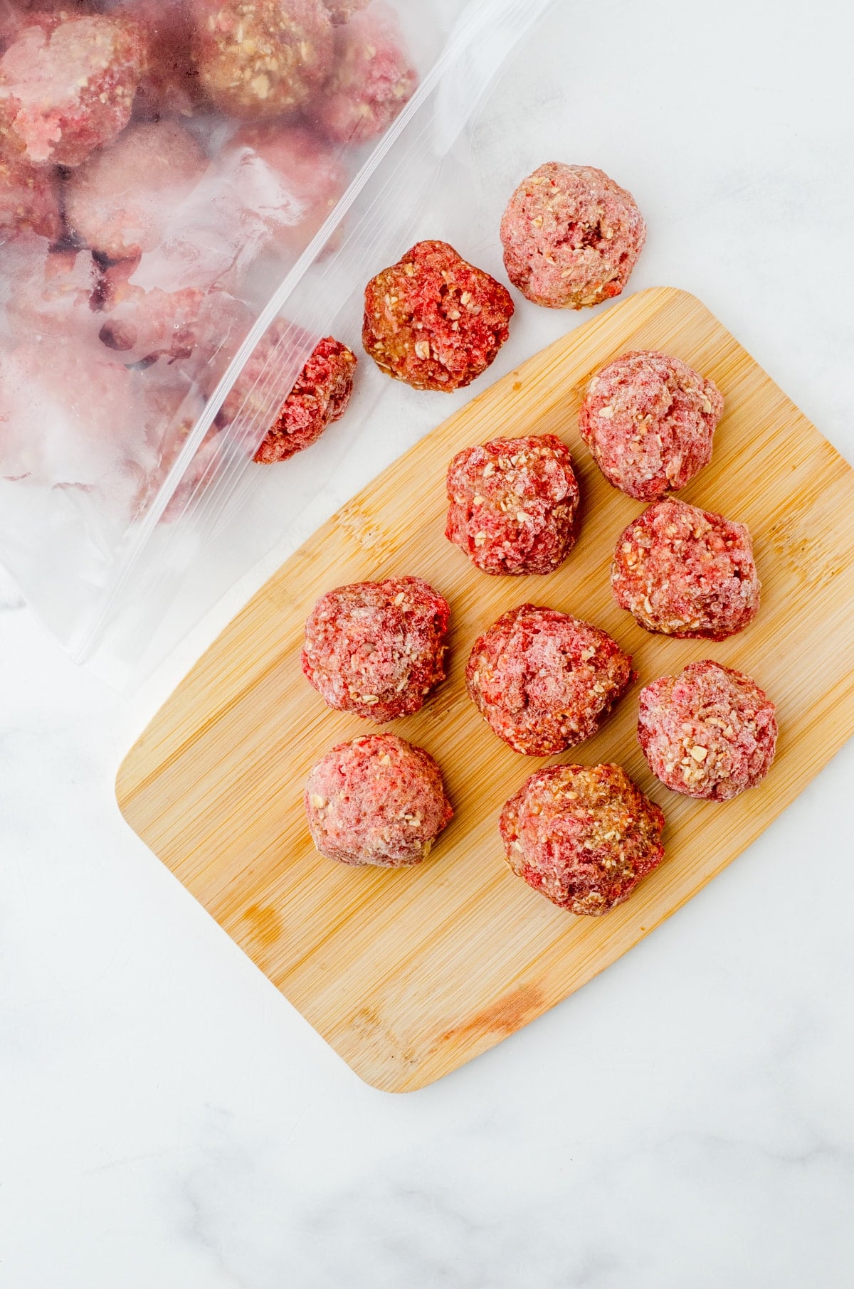 Frozen meatballs spilling out of a zip-top freezer bag