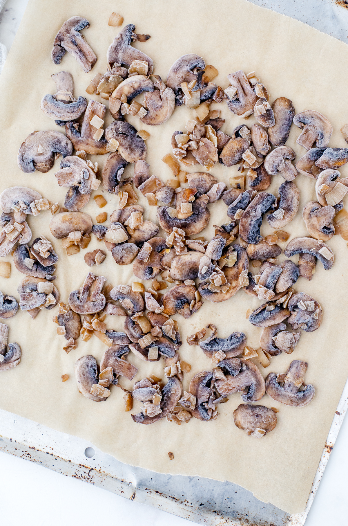 Frozen sauted mushrooms and onions on a parchment lined cookie sheet.