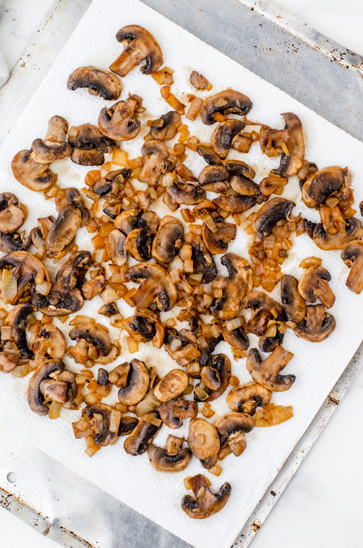 Sauted mushrooms and diced onions on a paper towel lined pan