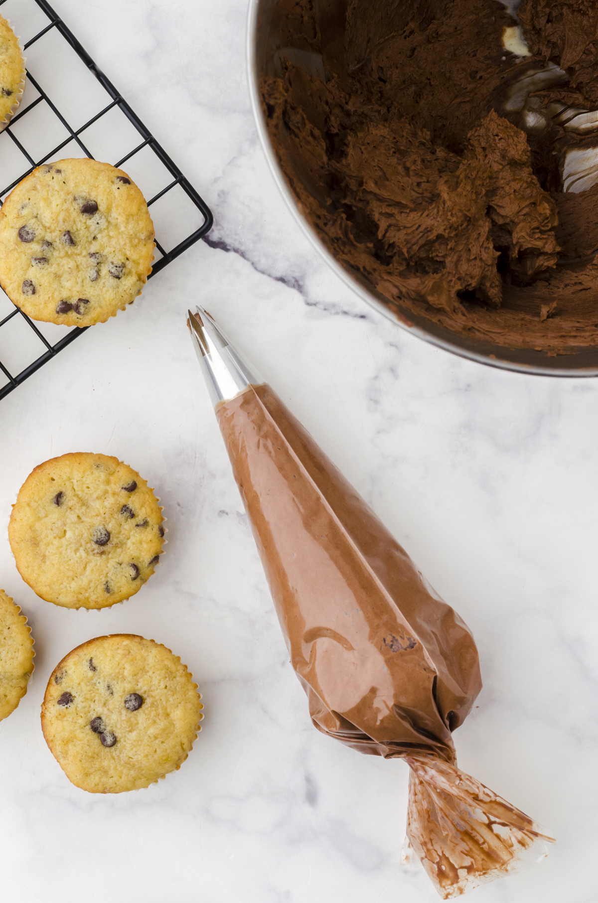 Chocolate frosting in a decorative icing bag with metal tip ready to use for this method for how to frost cupcakes.