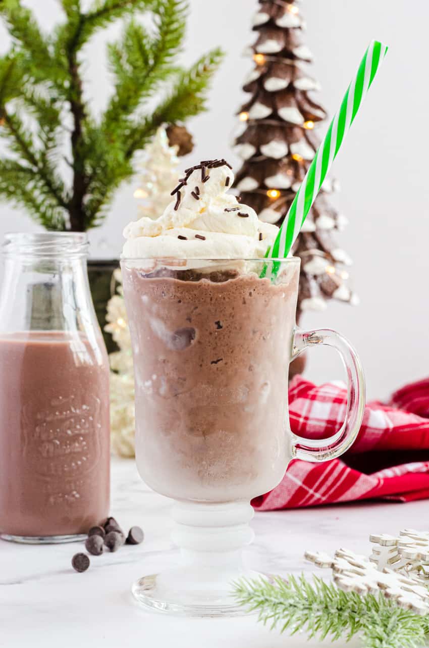 Clear mug with hot frozen chocolate in it with a green striped straw.