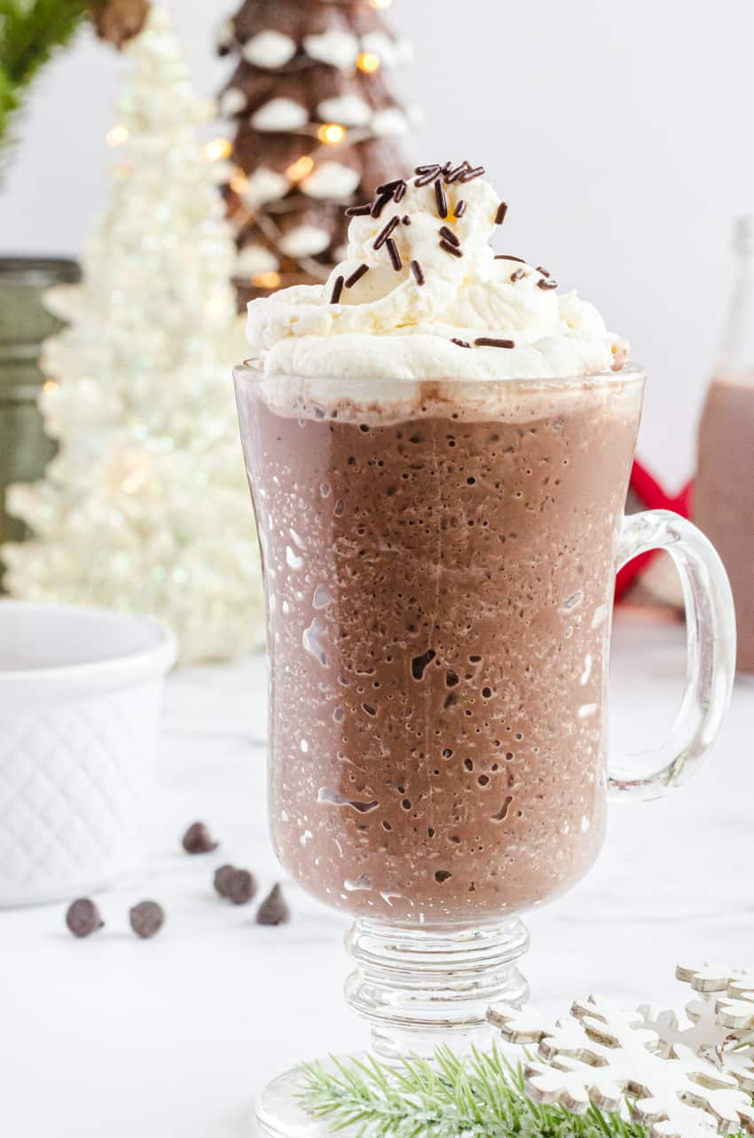 A mug of frozen hot chocolate with Christmas tree lights in the background.