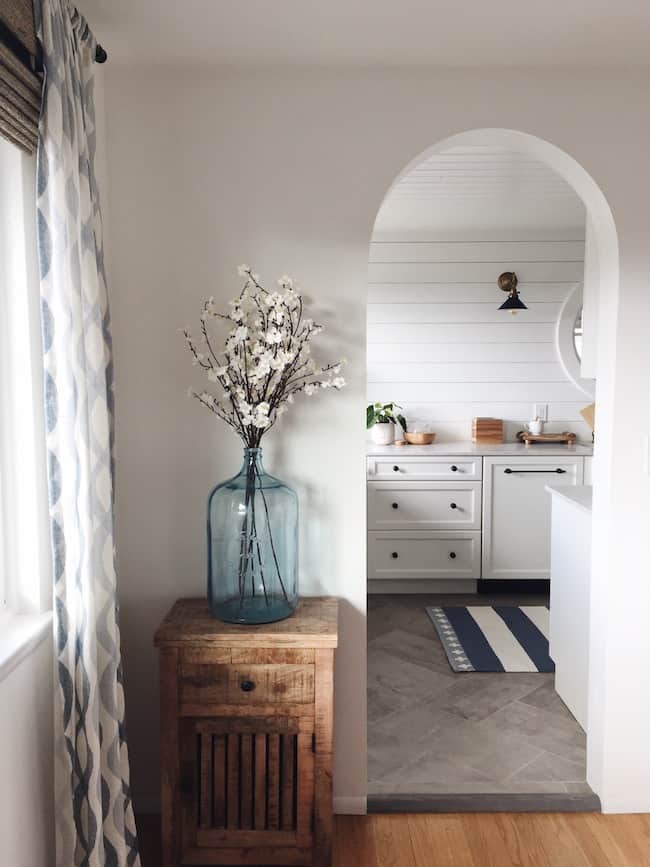 Archway doorway with flowers beside leading into a kitchen