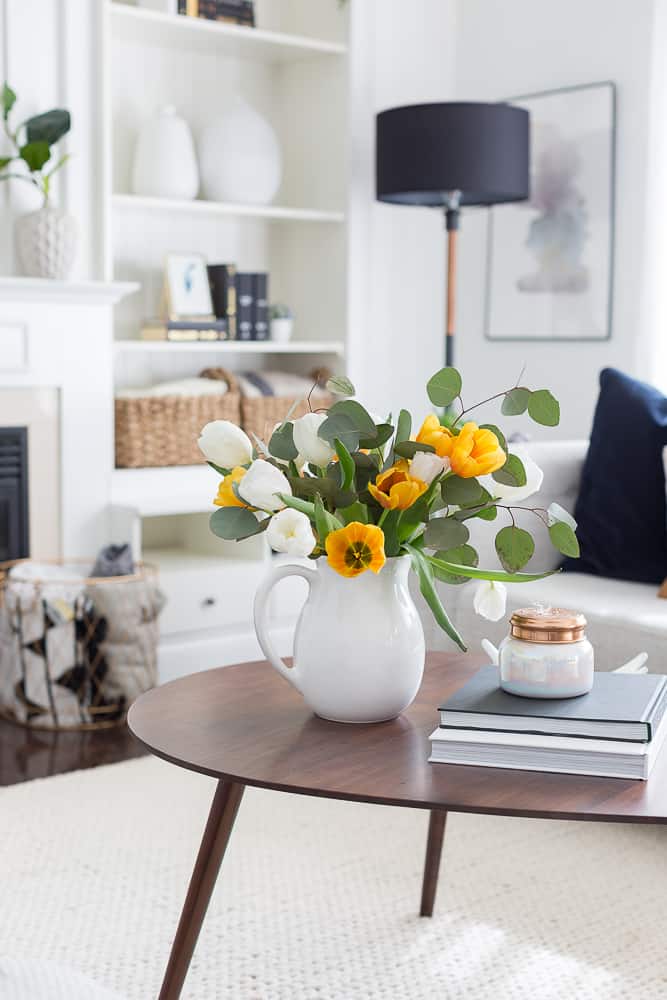 Coffee table in living room with bouquet of yellow and white flowers