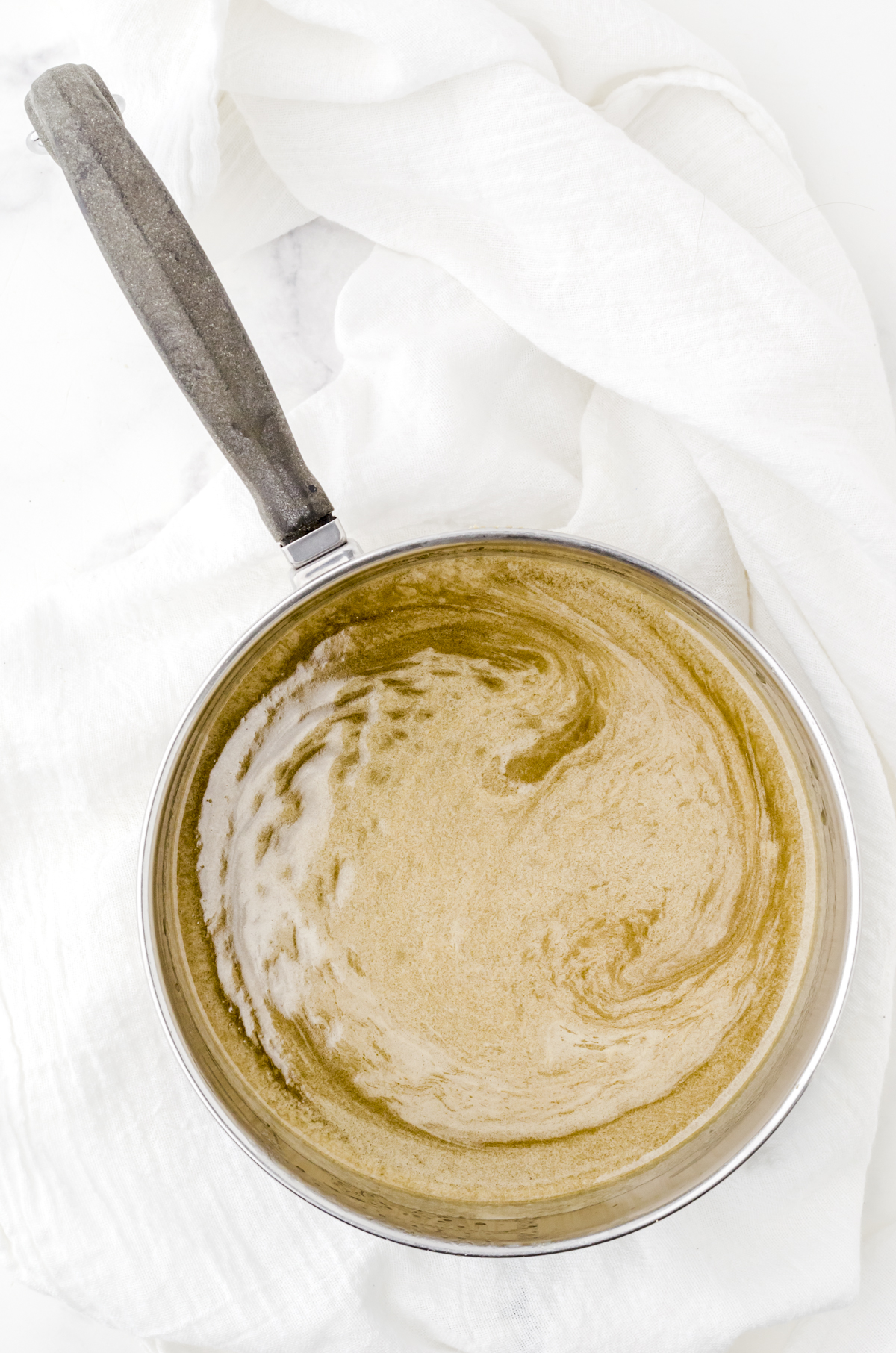 Ingredients for the poke and pour cake sauce melted in a sauce pan.