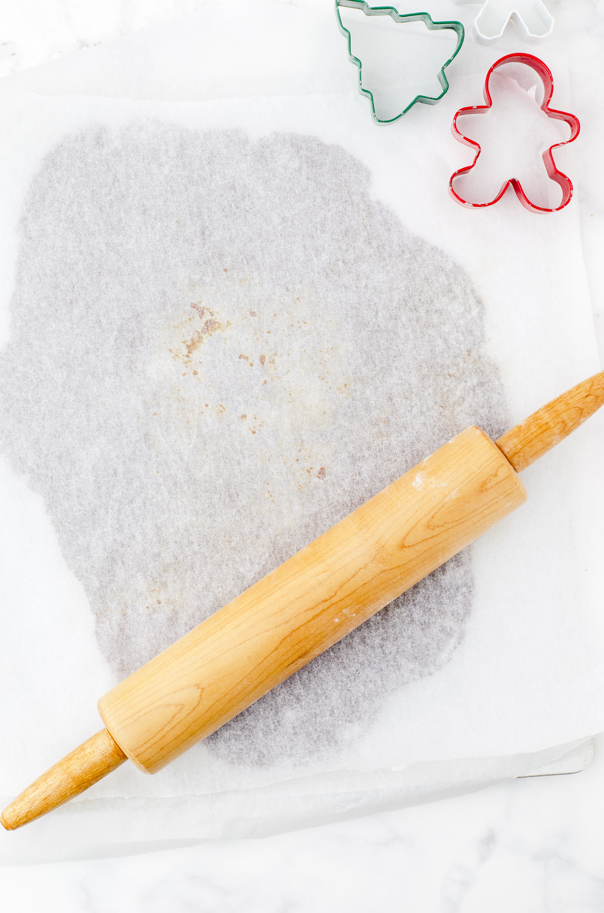 gingerbread cookie dough sandwiched between two sheets of parchment paper to roll out