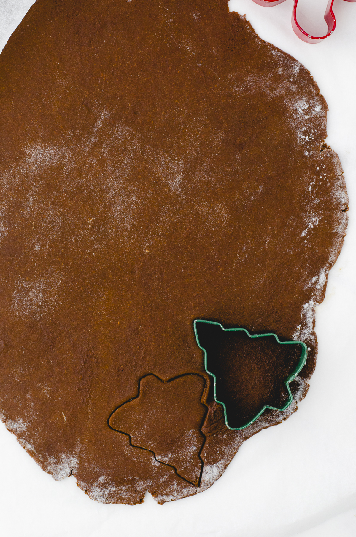 Gingerbread cookie dough with a Christmas tree cutter on it.