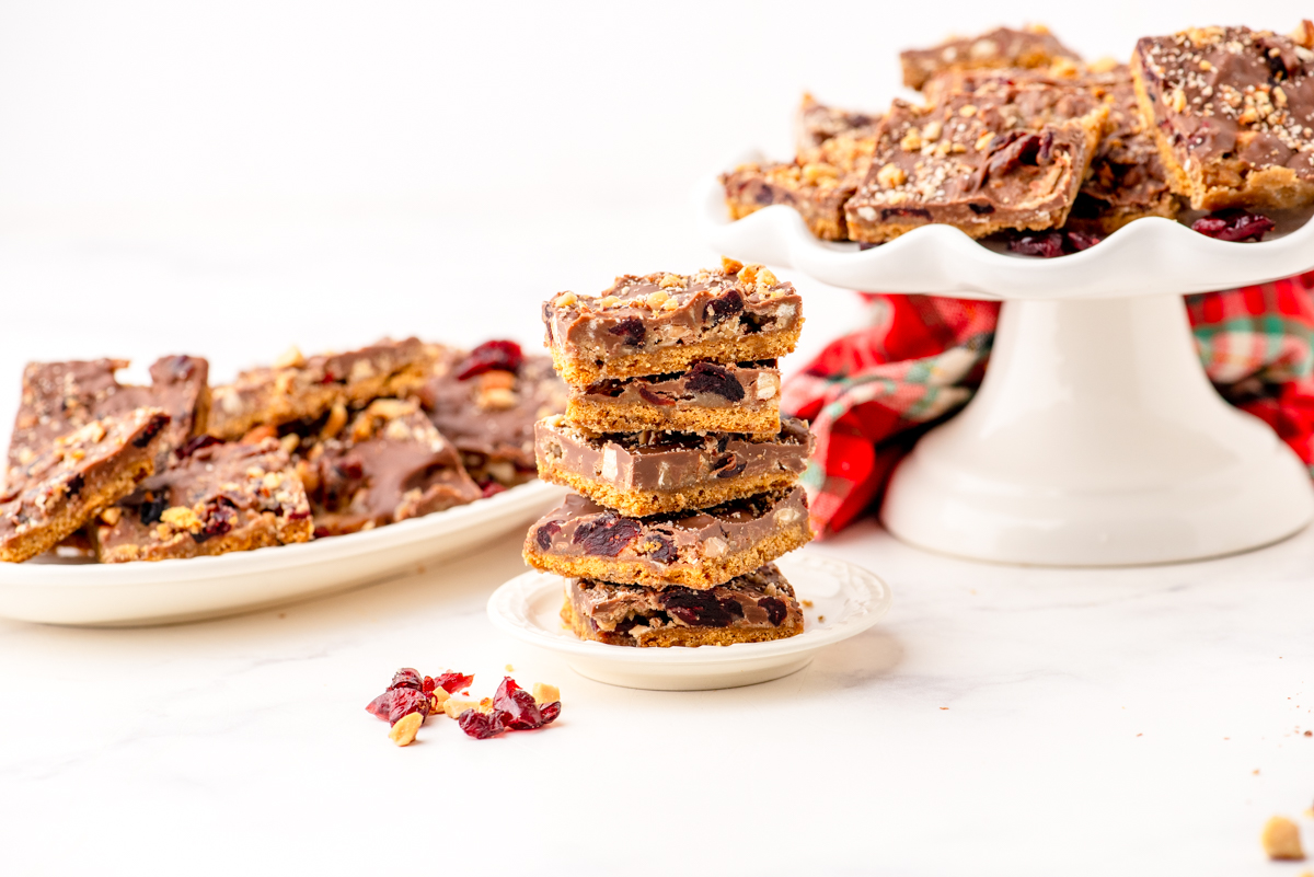 graham cracker toffee bars arranged on 2 different serving platters with a small stack of them sitting in front of them.