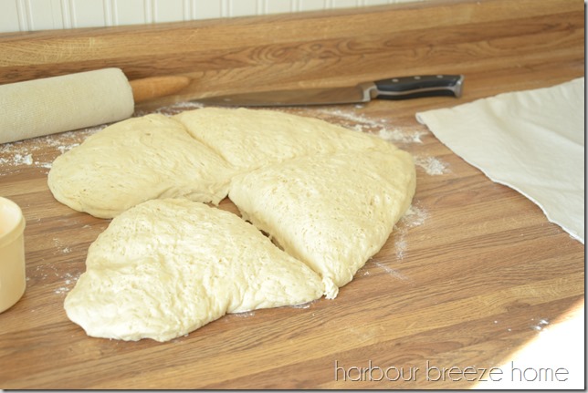 Old fashioned dinner roll dough turned out on a flour dusted countertop and cut into 4 equal portions.