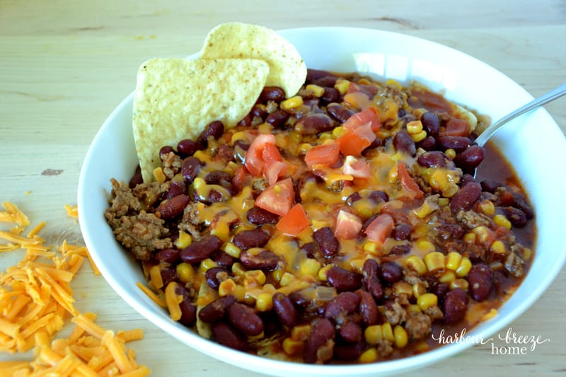 a bowl of taco soup with taco chips and grated cheese on the side