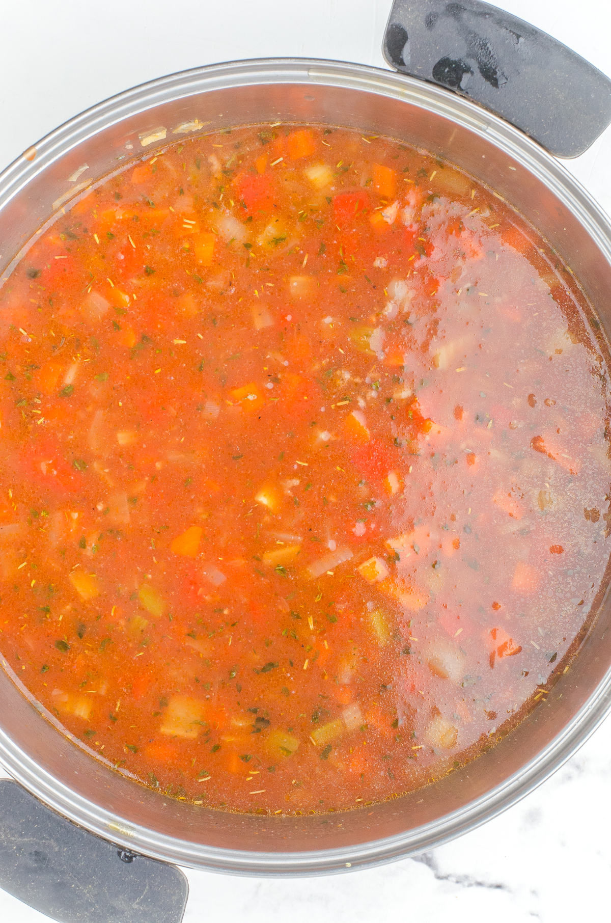 Hamburger rice soup with all the ingredients stirred together in a large stock pot - before it is simmered and cooked through.
