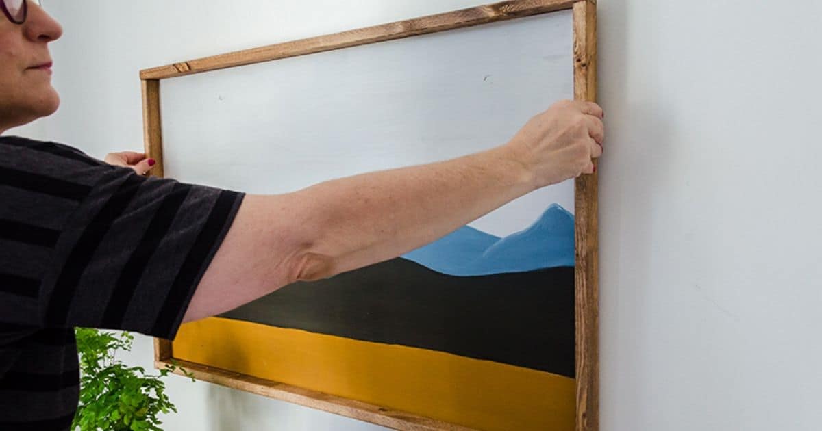 Woman hanging a big picture on the wall