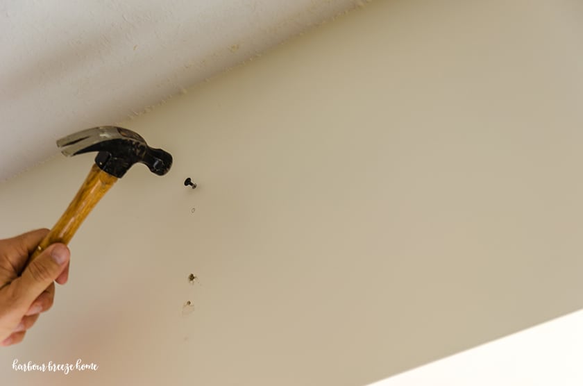 Using a nail to mark where a curtain rod bracket should go.