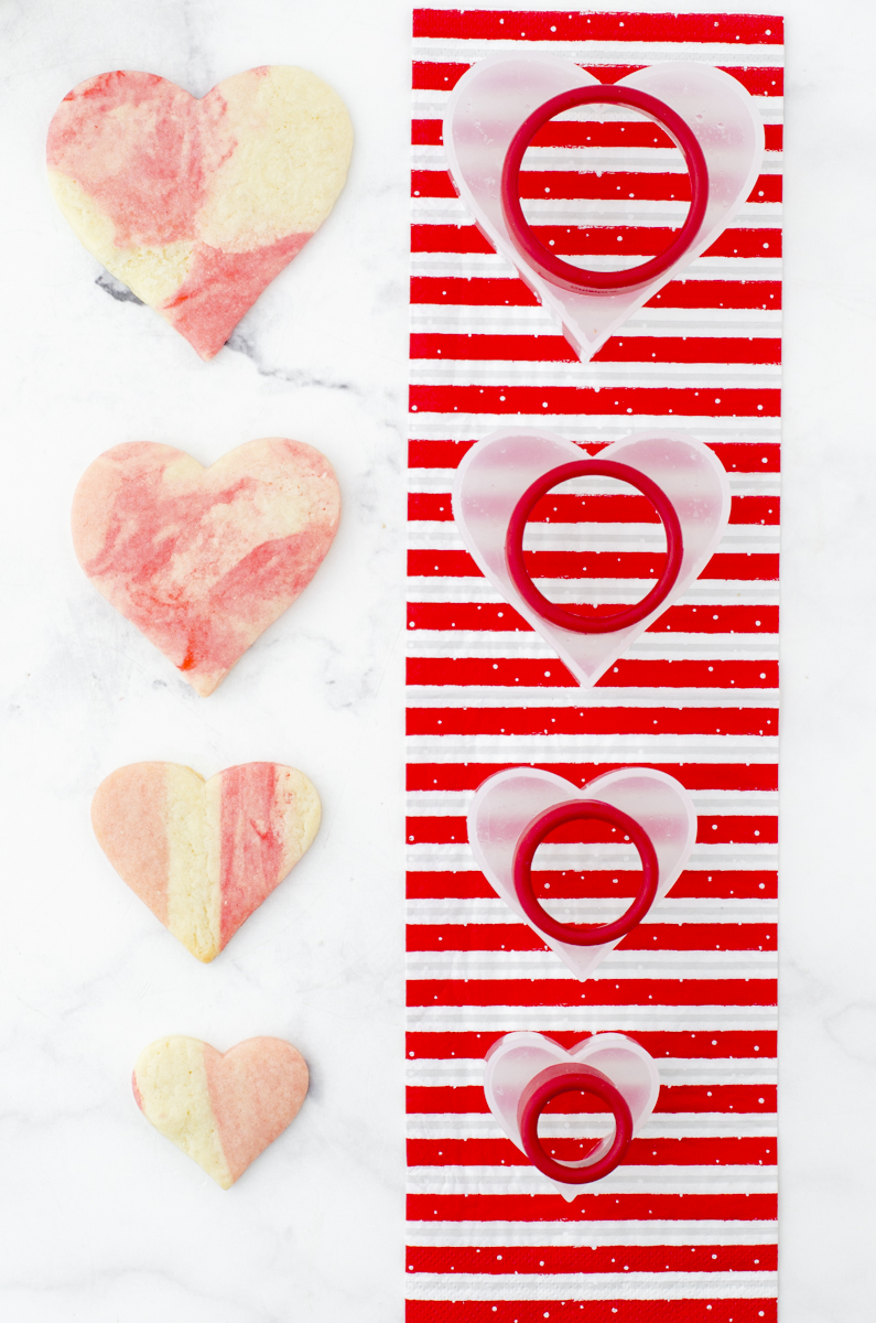 Heart sugar cookies sitting beside the heart shaped cookie cutter to illustrate that the dough doesn't spread during the baking process.