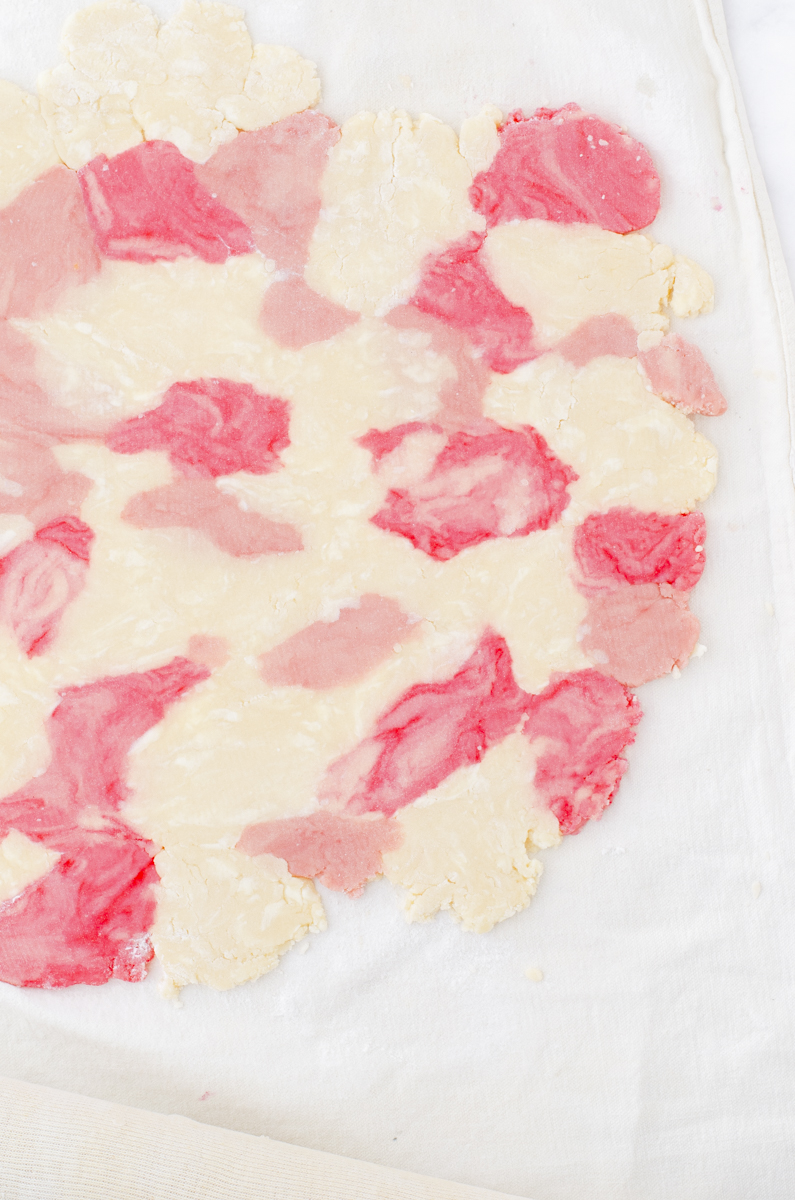 A sheet of rolled out marble colored sugar cookies dough.